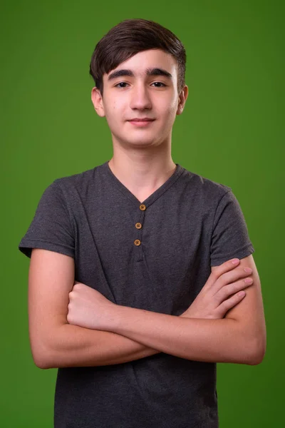 Young handsome Iranian teenage boy against green background — Stock Photo, Image