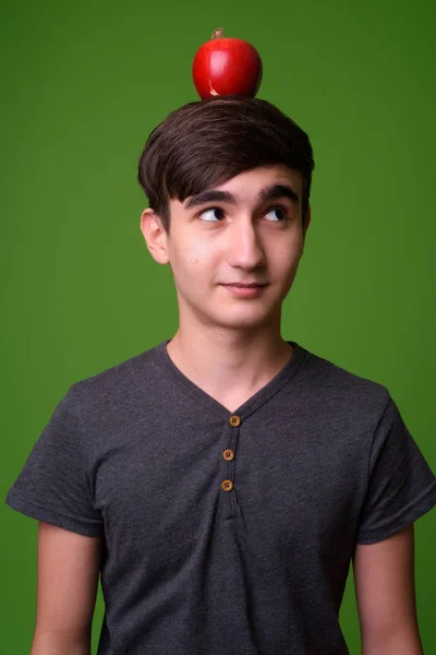 Young handsome Iranian teenage boy against green background — Stock Photo, Image