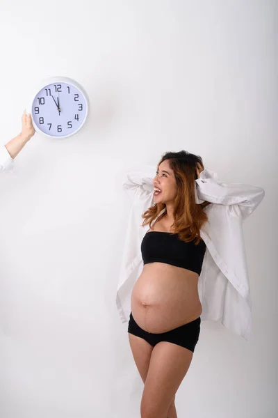 Портрет красивой молодой беременной азиатки, смотрящей на часы — стоковое фото