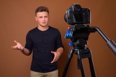 Yakışıklı delikanlı vlogging kahverengi arka plan stüdyo çekim