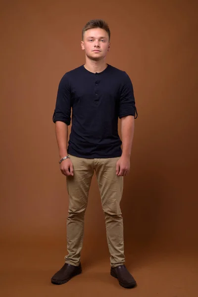Studio shot of young handsome man against brown background — Stock Photo, Image