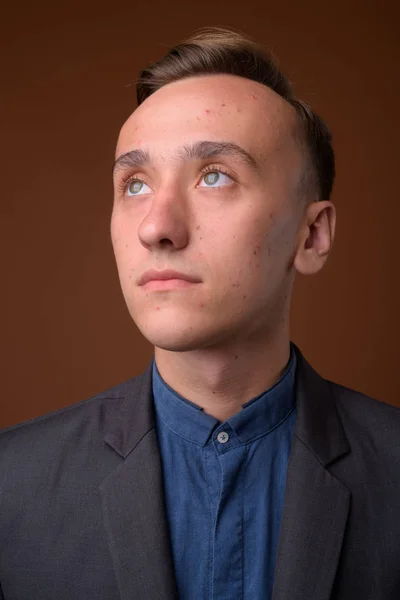 Studio shot of young handsome businessman against brown backgrou — Stock Photo, Image