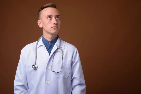 Genç yakışıklı adam doktor kahverengi zemin karşı — Stok fotoğraf
