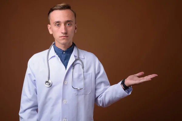Молодий красивий чоловік лікар на коричневому фоні — стокове фото
