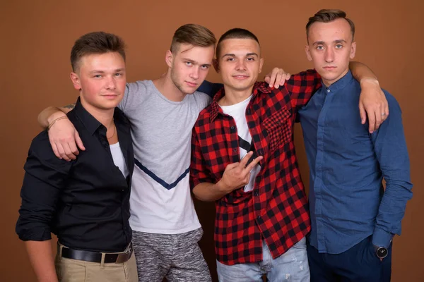 Чотири молодих красивих чоловіків разом на коричневому фоні — стокове фото