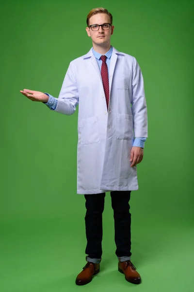 Jovem médico homem bonito com cabelo loiro contra backgrou verde — Fotografia de Stock