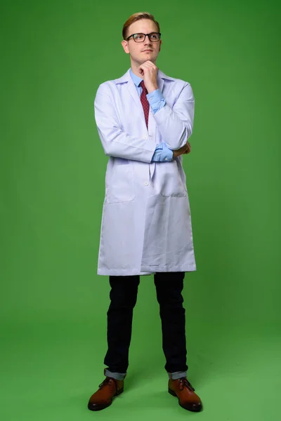 Jovem médico homem bonito com cabelo loiro contra backgrou verde — Fotografia de Stock