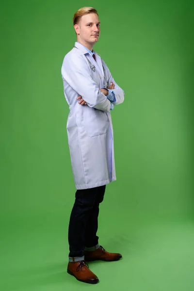 Jovem médico homem bonito com cabelo loiro contra backgrou verde — Fotografia de Stock