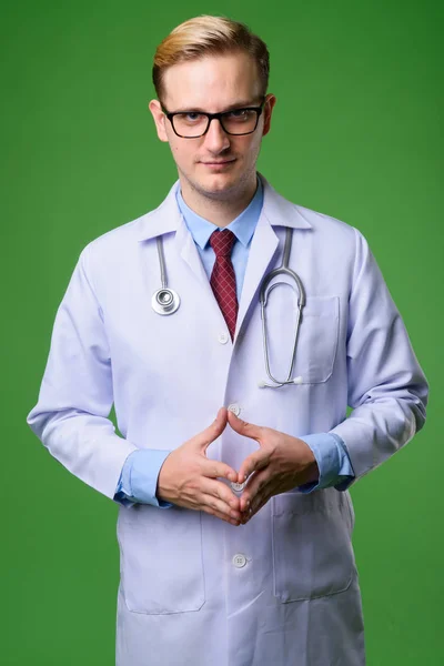 Pemuda tampan dokter dengan rambut pirang terhadap backgrou hijau — Stok Foto