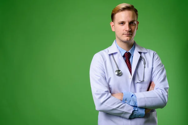 Giovane bel dottore uomo con i capelli biondi contro backgrou verde — Foto Stock