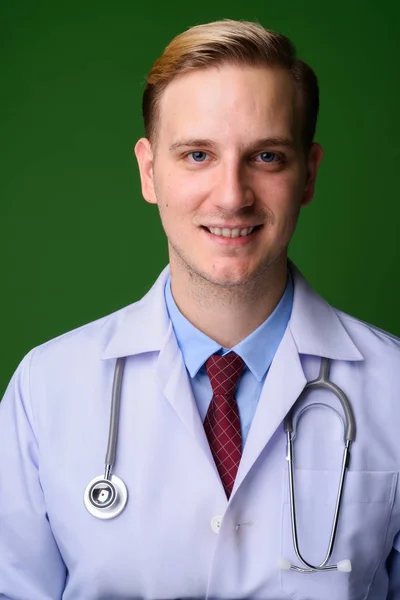 Молодий красивий чоловік лікар з світлим волоссям проти зеленого нарциса — стокове фото