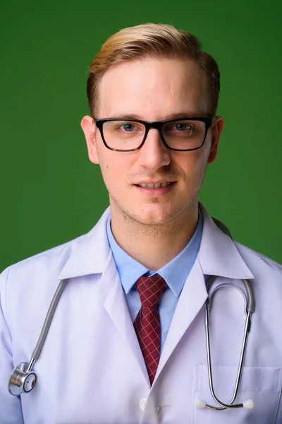 Joven hombre guapo médico con el pelo rubio contra el fondo verde — Foto de Stock