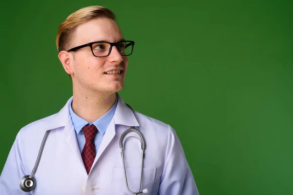 Joven hombre guapo médico con el pelo rubio contra el fondo verde — Foto de Stock