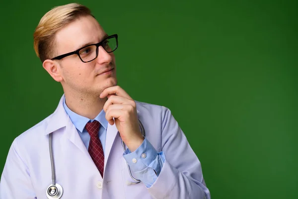 Doktor mladý pohledný muž s blond vlasy proti zelené poz — Stock fotografie