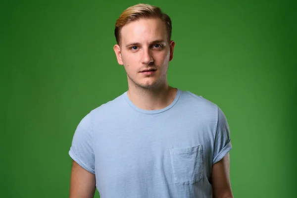 Jovem homem bonito com cabelo loiro contra fundo verde — Fotografia de Stock