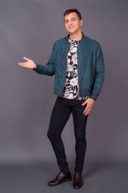 Genç ve yakışıklı adamın gri arka planda çekimleri.