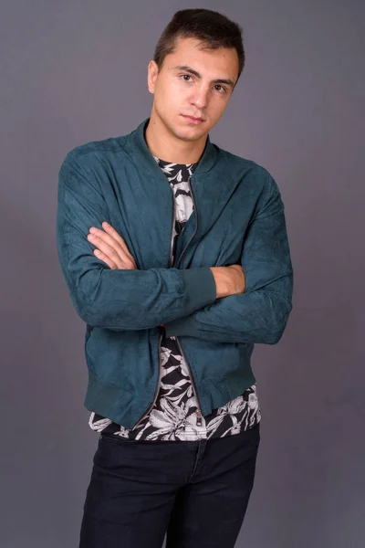 Studio shot of young handsome man against gray background — Stock Photo, Image