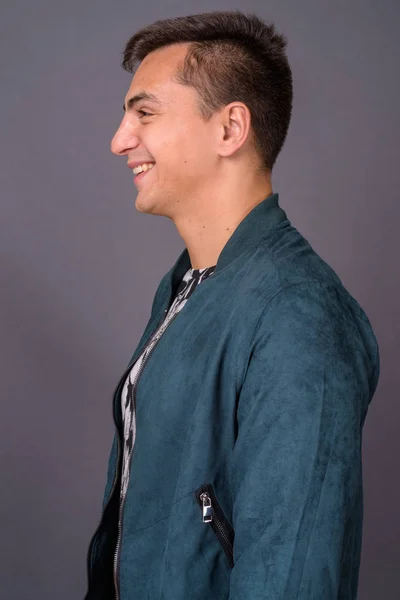 Vista de perfil de joven hombre guapo contra fondo gris — Foto de Stock