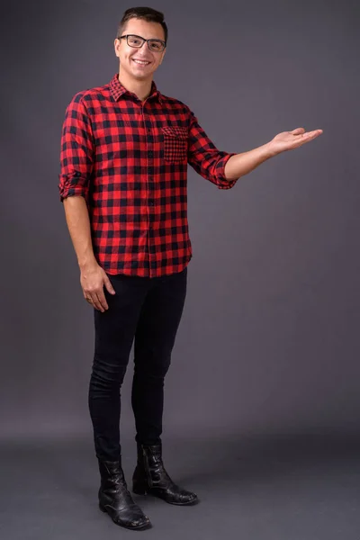 Studio shot of young handsome man against gray background — Stock Photo, Image