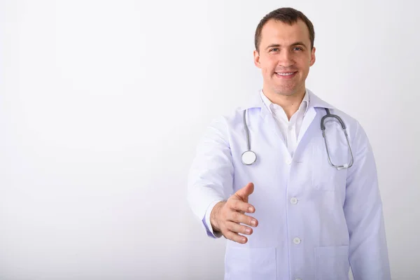 Студійний знімок молодого щасливого м'язистого лікаря, який посміхається, поки дає — стокове фото