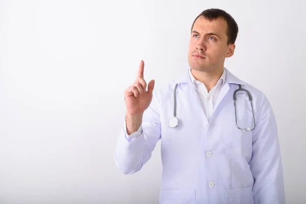Студійний знімок молодого м'язистого лікаря, який думає, вказуючи — стокове фото