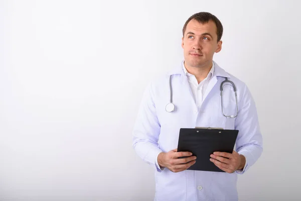 Studio shot of young muscular man doctor thinking while holding — Stock Photo, Image