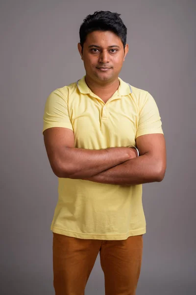 Portrait of young Indian man against gray background