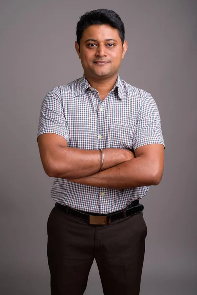 Portrait of young Indian businessman against gray background