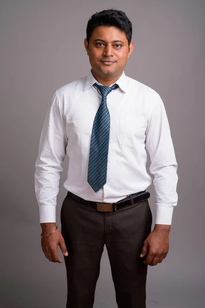 Портрет молодого индийского бизнесмена на сером фоне — стоковое фото