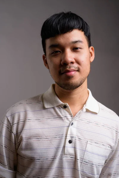 Porträt eines jungen Asiaten vor grauem Hintergrund — Stockfoto