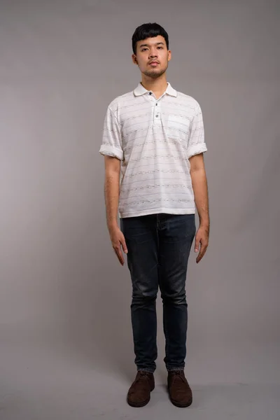 Portret van jonge Aziatische man tegen grijze achtergrond — Stockfoto