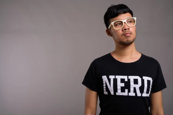 Młody Azji nerd człowiek noszenie okulary na szare tło — Zdjęcie stockowe