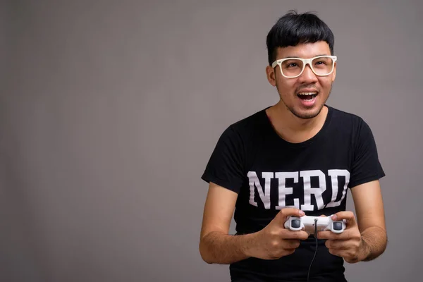 Joven asiática nerd hombre usando anteojos contra gris fondo —  Fotos de Stock