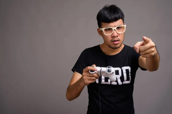 Junger asiatischer Nerd mit Brille vor grauem Hintergrund — Stockfoto