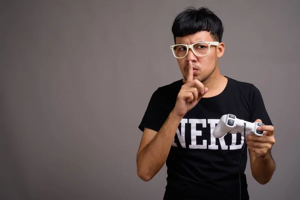 Junger asiatischer Nerd mit Brille vor grauem Hintergrund — Stockfoto