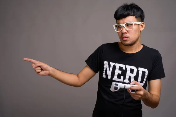 Joven asiática nerd hombre usando anteojos contra gris fondo —  Fotos de Stock