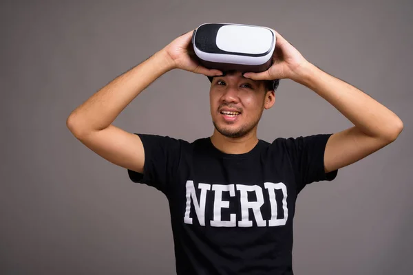 Young Asian nerd man using virtual reality headset