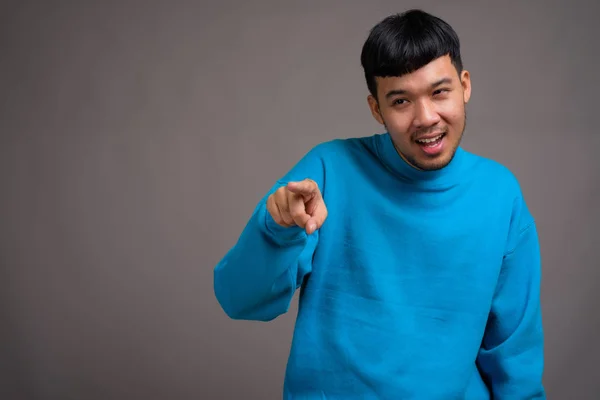 Portrét mladého asijského muže na šedém pozadí — Stock fotografie
