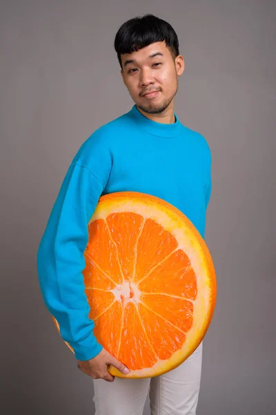 Porträt eines jungen asiatischen Mannes mit einem großen Stück Orange — Stockfoto