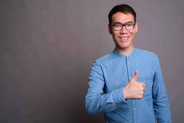 Portrét mladého asijského podnikatele na šedém pozadí — Stock fotografie