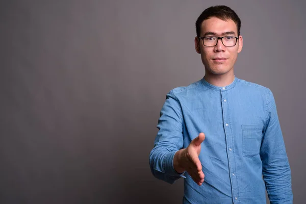 Retrato de jovem empresário asiático contra fundo cinza — Fotografia de Stock