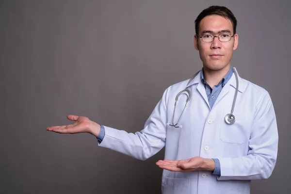 Młody Azji człowiek lekarz na szarym tle — Zdjęcie stockowe