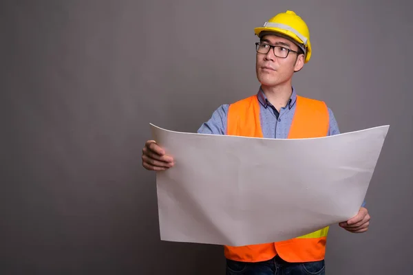 Joven asiático hombre construcción trabajador contra gris fondo —  Fotos de Stock