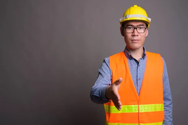 Молодий азіатський будівельник на сірому фоні — стокове фото