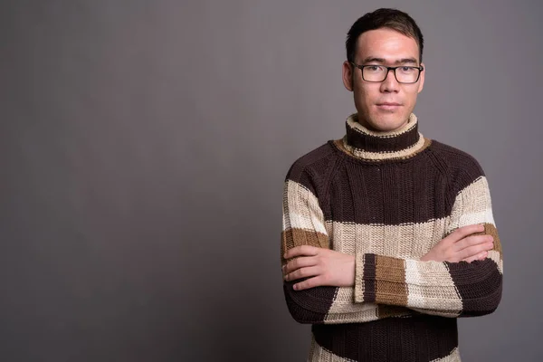 Joven hombre asiático con jersey de cuello alto contra fondo gris — Foto de Stock