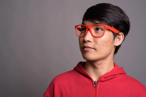 アジア系の若い男は灰色と眼鏡を身に着けている赤いジャケット — ストック写真