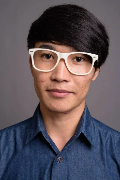 Young Asian man wearing eyeglasses looking smart against gray ba — Stock Photo, Image