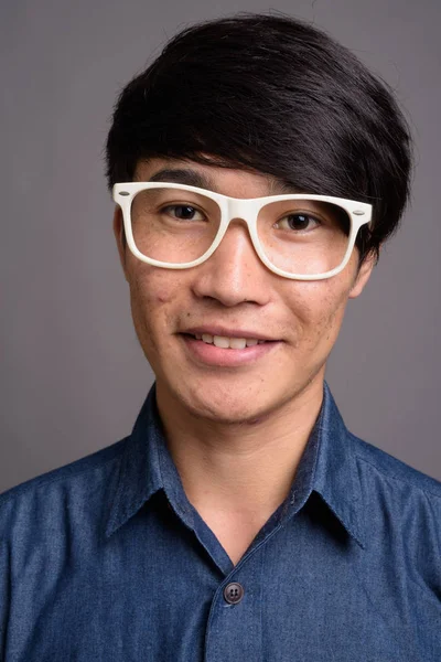 Jonge Aziatische man dragen brillen op zoek slimme tegen grijze ba — Stockfoto