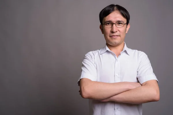 Jong aziatische nerd man het dragen van bril tegen grijs achtergrond — Stockfoto