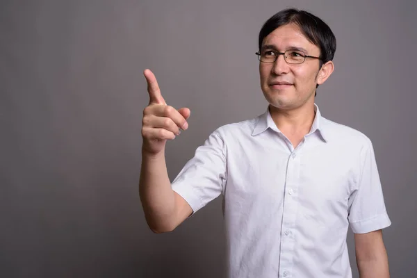 Joven asiática nerd hombre usando anteojos contra gris fondo —  Fotos de Stock